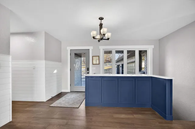 a dining room with wooden floor a chandelier a wooden table and chairs