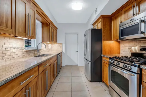 a kitchen with stainless steel appliances granite countertop a stove a refrigerator and a sink