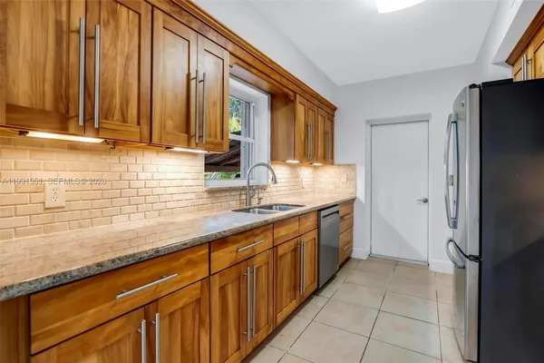 a kitchen with stainless steel appliances granite countertop a refrigerator and a sink