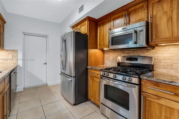 a kitchen with granite countertop a stove microwave and refrigerator