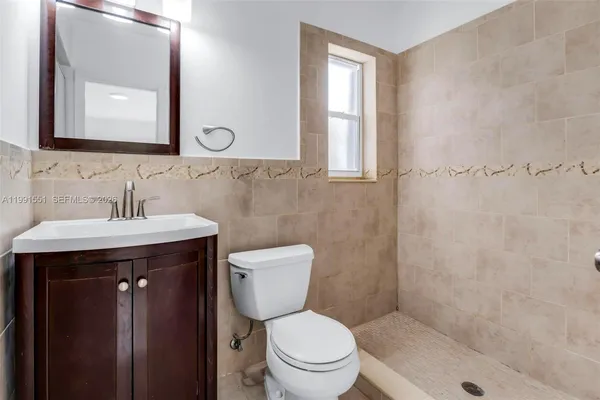 a bathroom with a toilet a sink a mirror and a shower