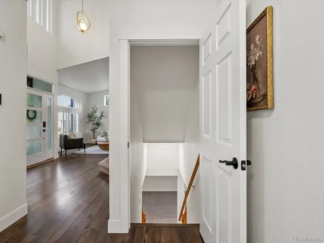 a view of an empty room with wooden floor and a ceiling fan