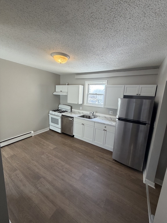 a kitchen with white cabinets and wooden floor