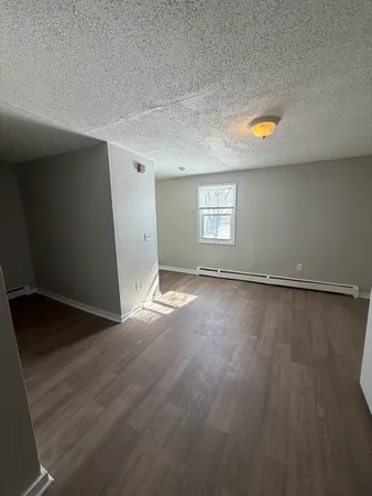an empty room with wooden floor and natural light