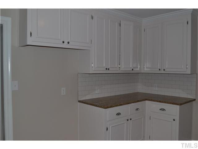 2524 Pickett Road Durham, NC 27705 - Photo 4 of 20 Other side of the kitchen, lots of kitchen cabinets, large planked wood composite floors, lots of natural light from the windows. Granite counter top, tile backsplash, new hardware. Kitchen