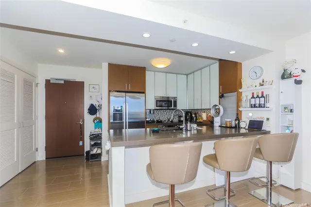 a kitchen with stainless steel appliances kitchen island granite countertop a refrigerator and chairs
