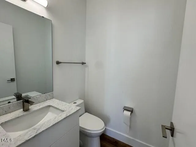 a bathroom with a granite countertop sink vanity mirror and toilet