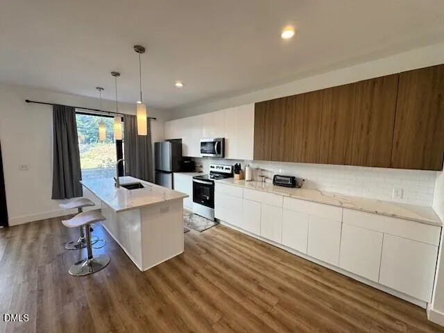 a kitchen with white cabinets a sink dishwasher and a stove with wooden floor