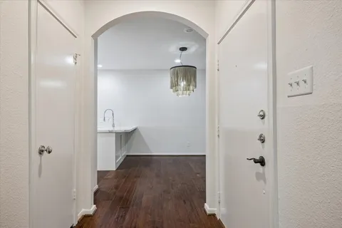 a view of a hallway with wooden floor and a bathroom