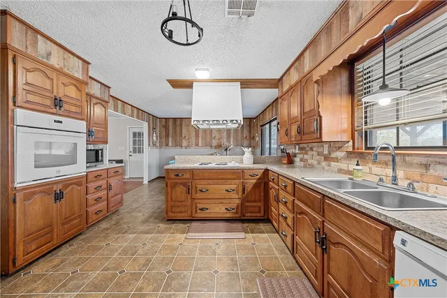 a large kitchen with stainless steel appliances granite countertop a sink and cabinets