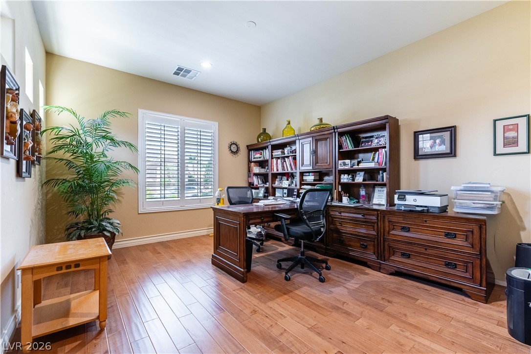 3661 Riley Ann Avenue Las Vegas, NV 89139 - Photo 7 of 42 Hardwood floors and generous natural light create an inviting home office space, perfect for productivity.