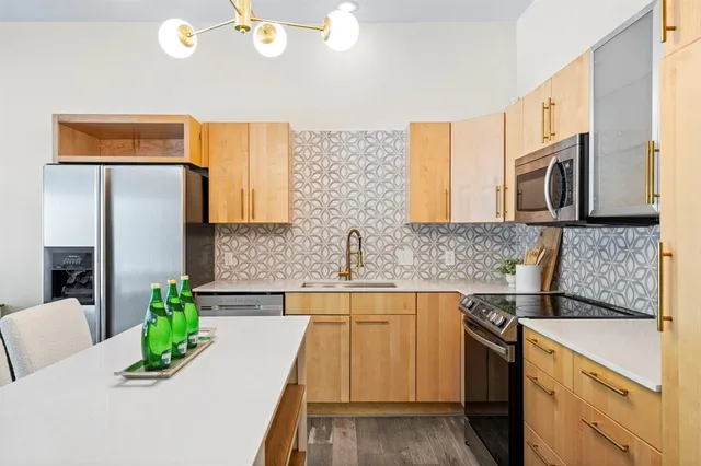 a kitchen with stainless steel appliances granite countertop a sink a stove top oven a chimney and a center island