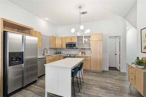 a kitchen with stainless steel appliances a refrigerator a sink a stove cabinets and wooden floor