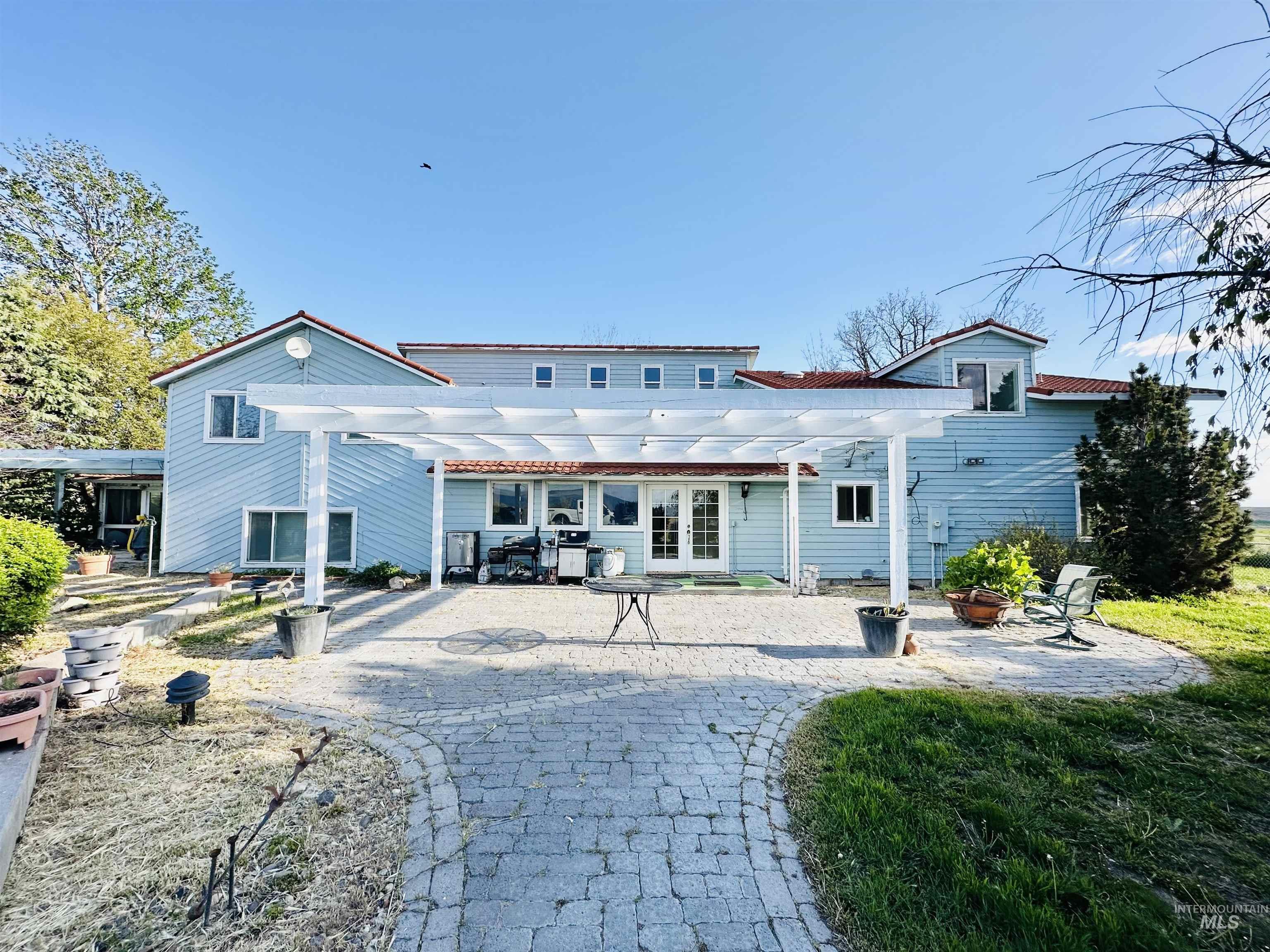 Expansive paver patio with a white pergola offering outdoor living space