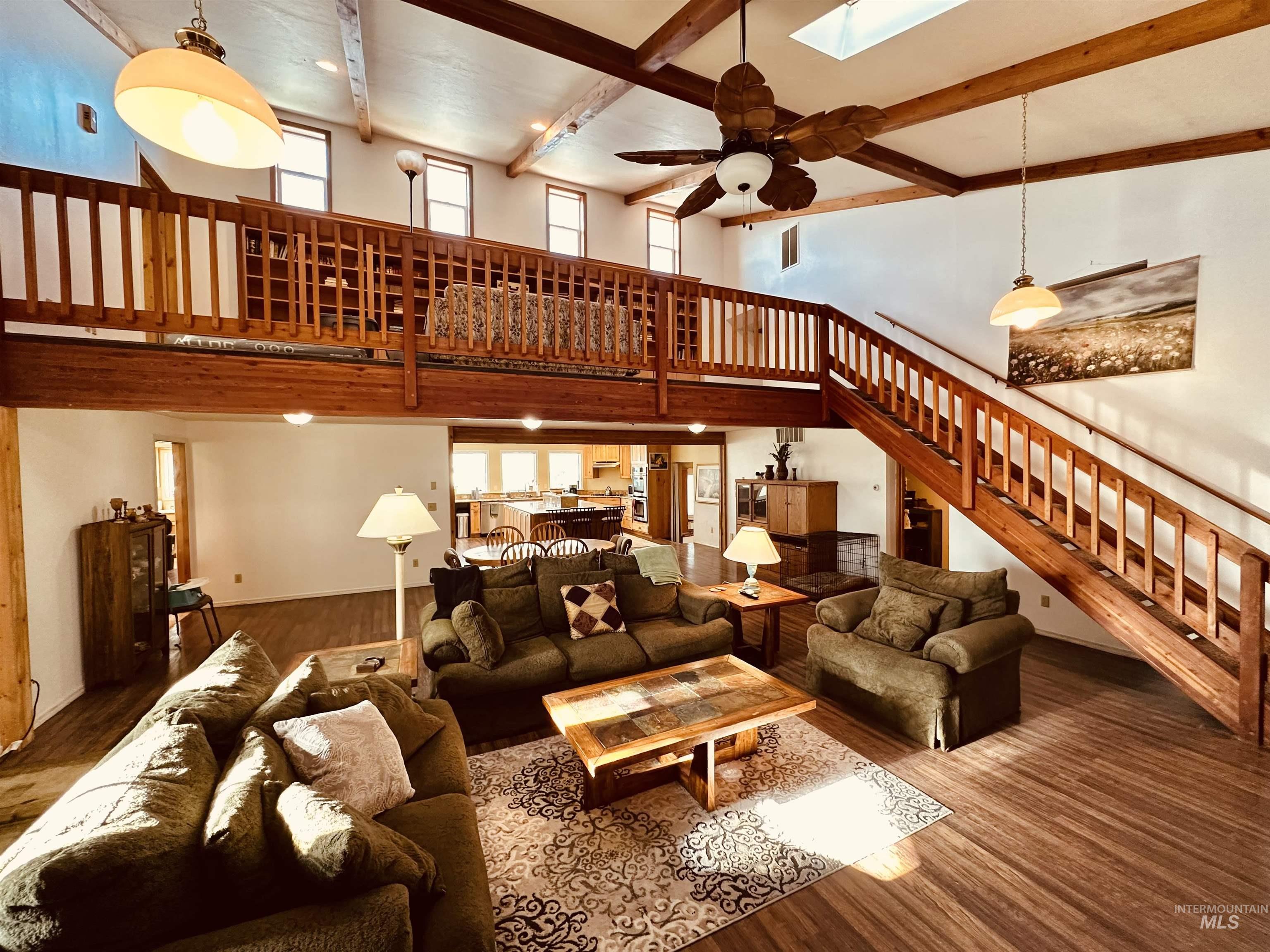 1049 Grand Avenue Nyssa, OR 97913 - Photo 13 of 50 Expansive living area featuring soaring ceilings with exposed wood beams, a prominent wood staircase, a loft with a wood railing, and wood-finish flooring