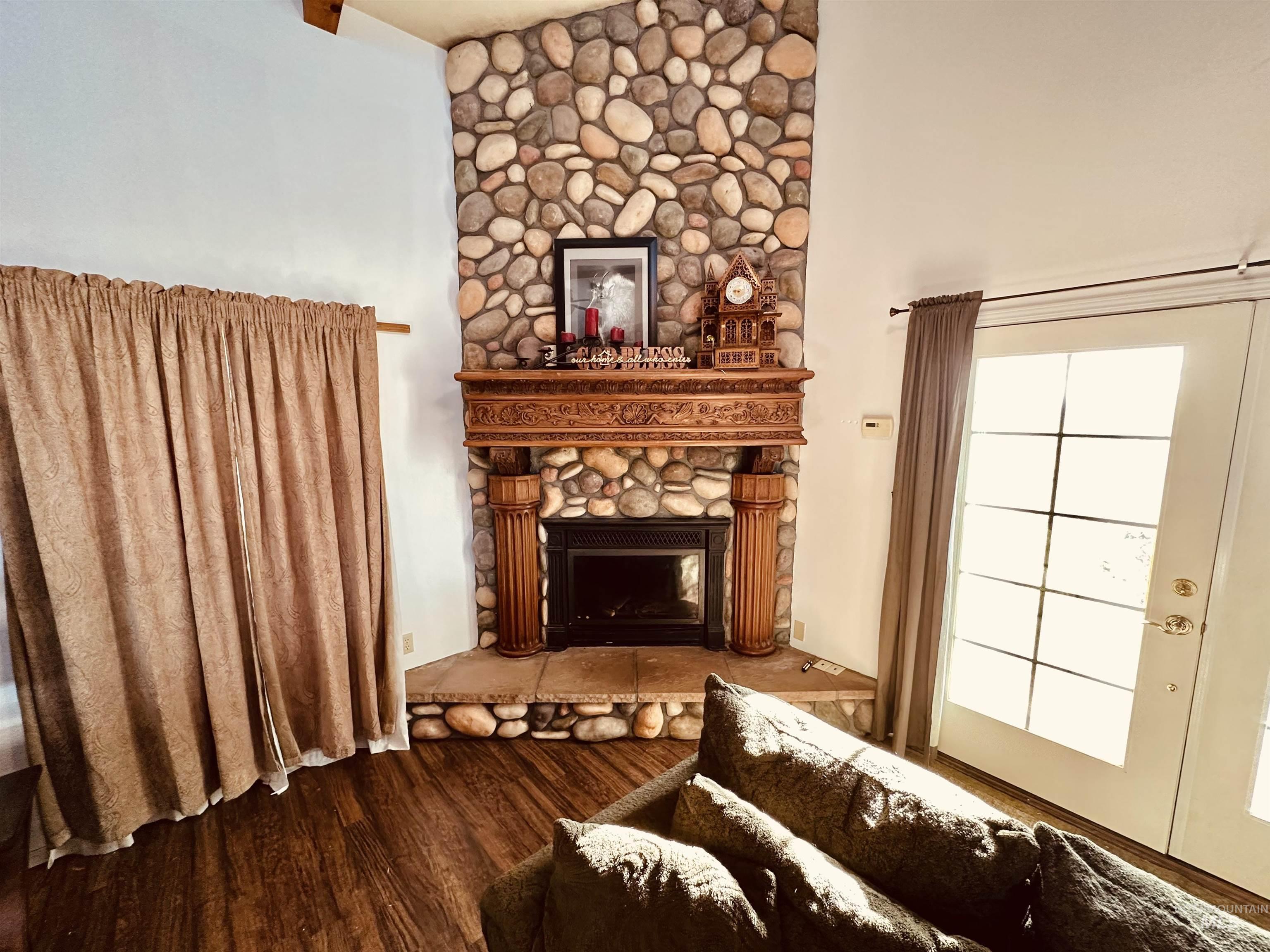1049 Grand Avenue Nyssa, OR 97913 - Photo 14 of 50 Corner fireplace featuring a river rock surround, an ornate wood mantel, and a stone hearth