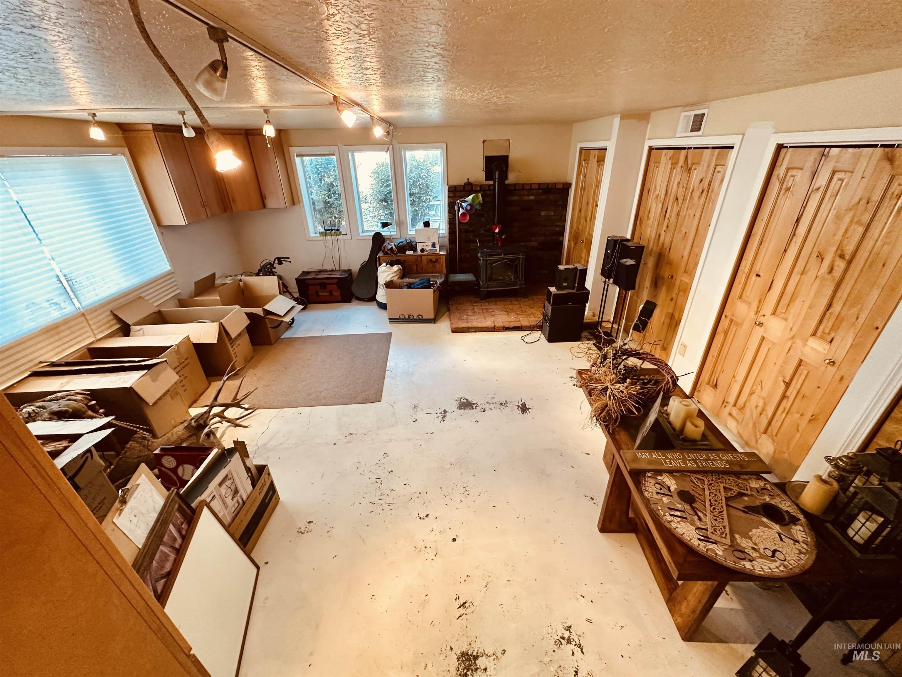 1049 Grand Avenue Nyssa, OR 97913 - Photo 15 of 50 Spacious room featuring multiple windows, recessed cabinetry, a brick hearth with a wood-burning stove, and natural wood doors