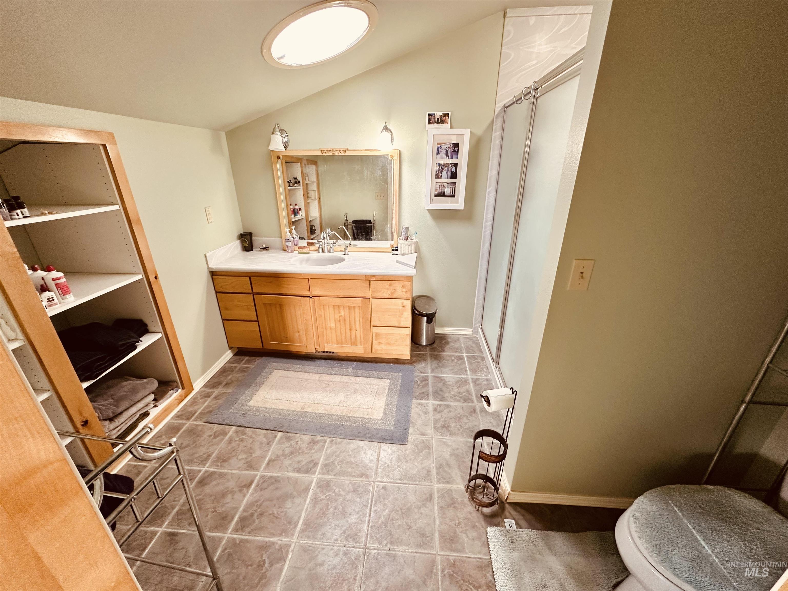 1049 Grand Avenue Nyssa, OR 97913 - Photo 18 of 50 Vaulted ceiling with a skylight, wood-finish vanity with a built-in sink, framed vanity mirror, and a glass-enclosed shower