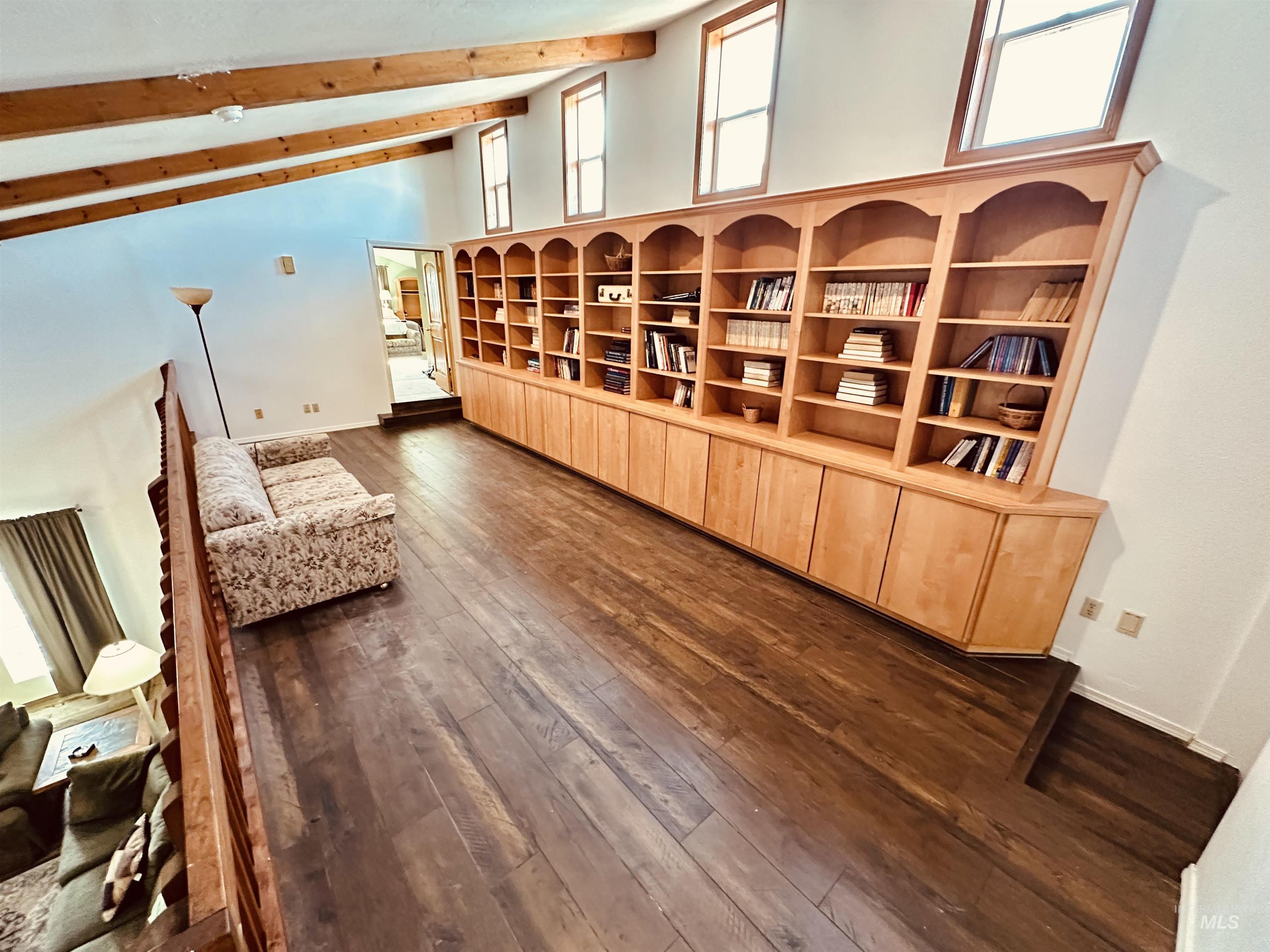 1049 Grand Avenue Nyssa, OR 97913 - Photo 19 of 50 Expansive loft area featuring a full-length built-in blonde wood bookcase, wood-finish flooring, exposed ceiling beams, and multiple windows