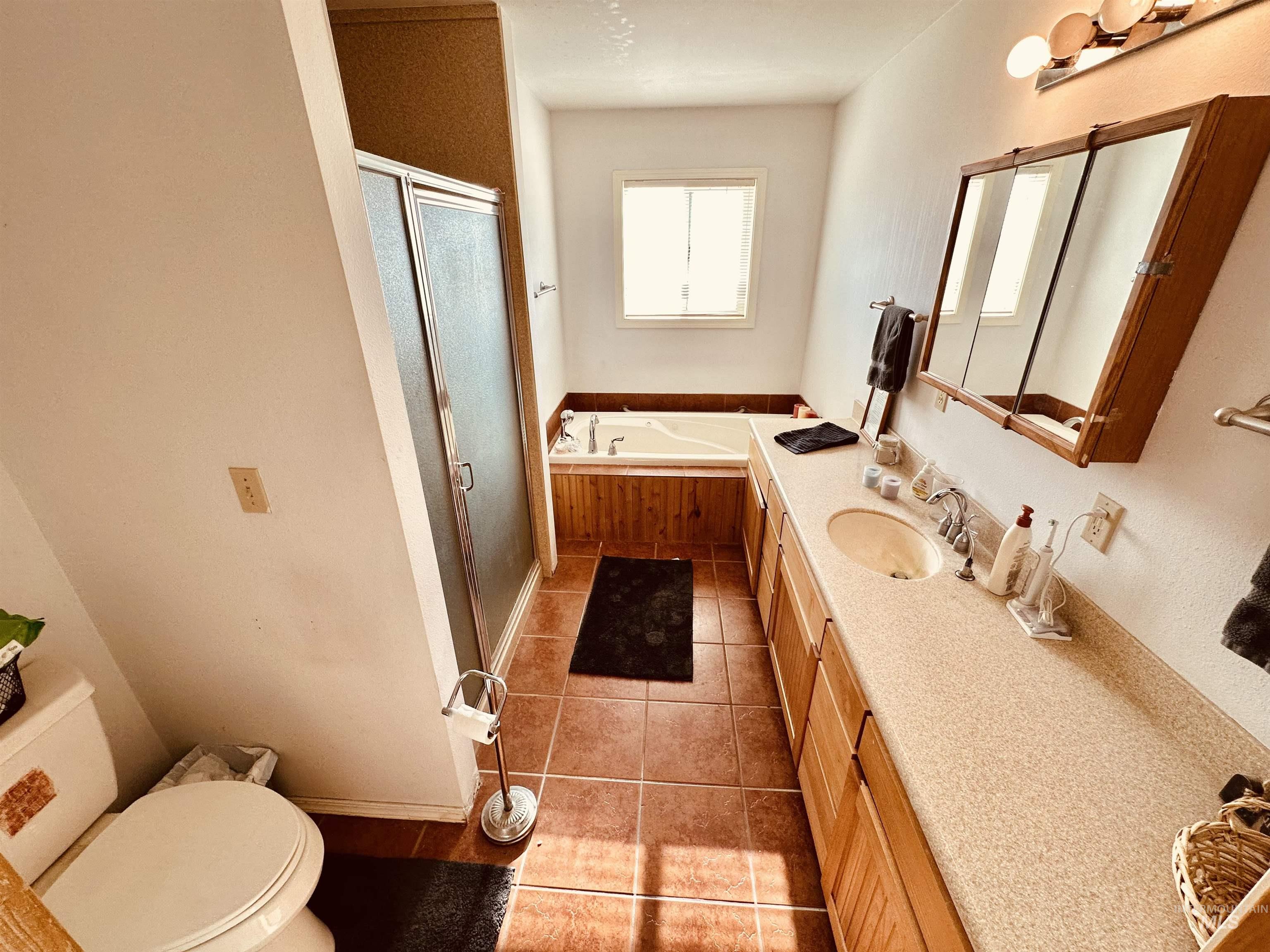 1049 Grand Avenue Nyssa, OR 97913 - Photo 24 of 50 Full bathroom featuring a dual vanity with integrated sinks, a tiled shower enclosure, an elongated soaking tub with wood paneling, and ceramic tile flooring