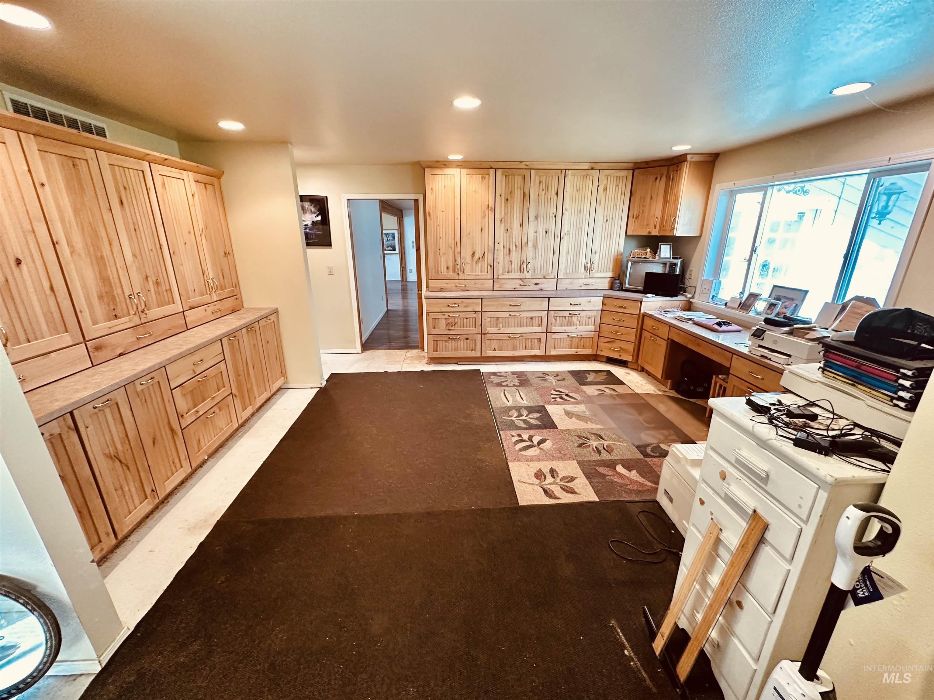 1049 Grand Avenue Nyssa, OR 97913 - Photo 29 of 50 Expansive room featuring extensive built-in light wood cabinetry, recessed lighting, a built-in desk area with a window, and mixed flooring materials