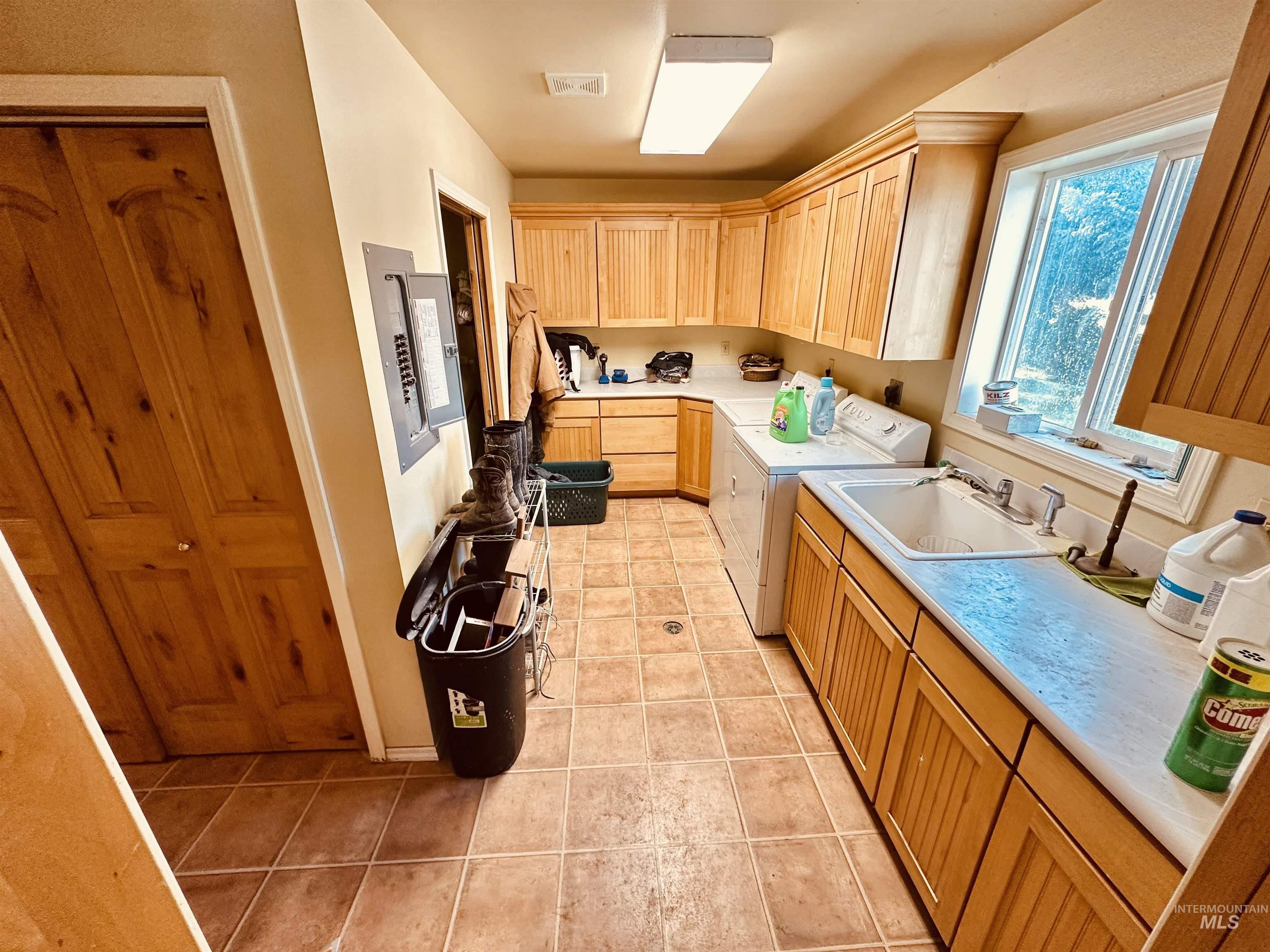 1049 Grand Avenue Nyssa, OR 97913 - Photo 30 of 50 Functional utility room featuring extensive natural wood cabinetry, tile flooring, a large utility sink, and a window for natural light