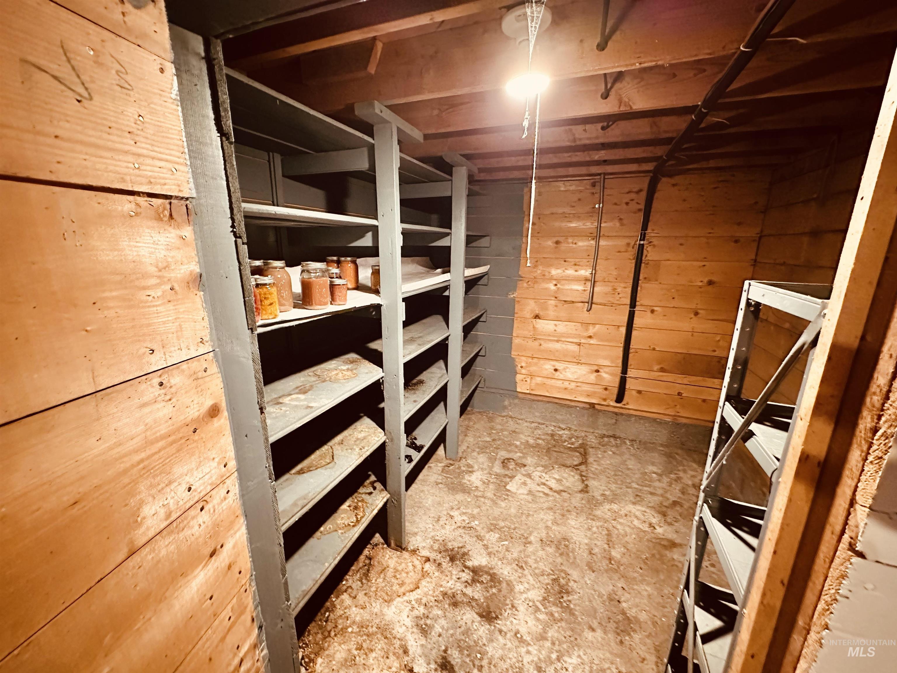 1049 Grand Avenue Nyssa, OR 97913 - Photo 33 of 50 Basement storage area featuring extensive built-in wooden shelving, additional metal shelving, exposed wood beam ceiling, and wood-paneled walls