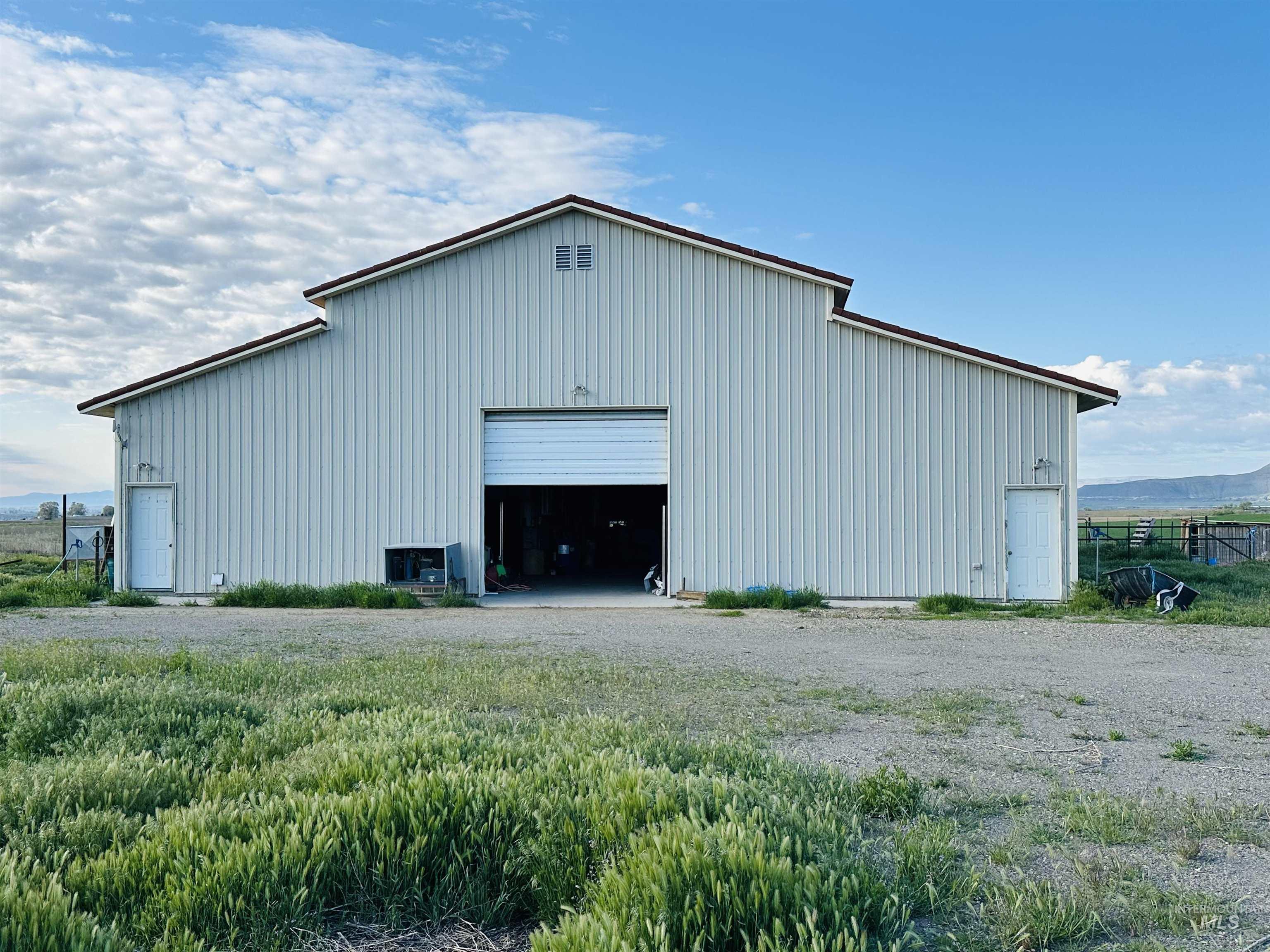 1049 Grand Avenue Nyssa, OR 97913 - Photo 36 of 50 Metal-sided barn structure featuring a brown-trimmed gable roof, central roll-up door, and two pedestrian entry doors 40x60 shop