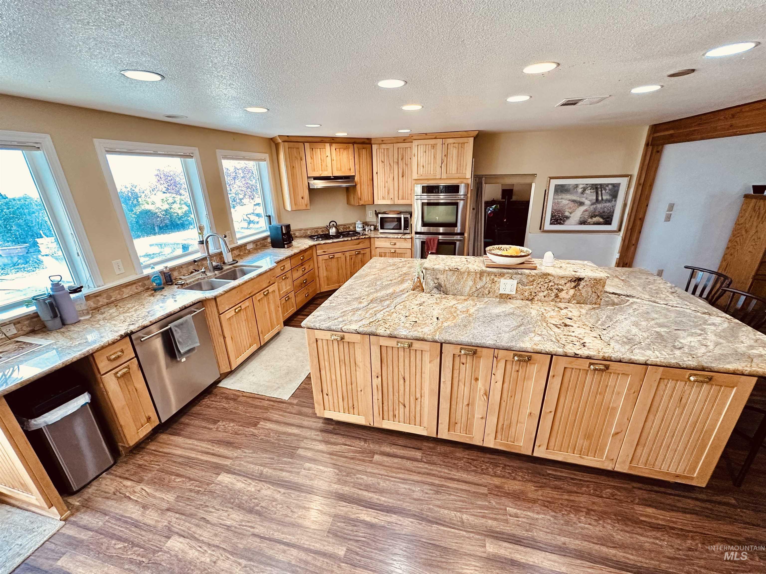 1049 Grand Avenue Nyssa, OR 97913 - Photo 5 of 50 Spacious kitchen featuring a large central island with a granite-look countertop, light wood-finish cabinetry, stainless steel appliances, abundant recessed lighting, and wood-finish flooring