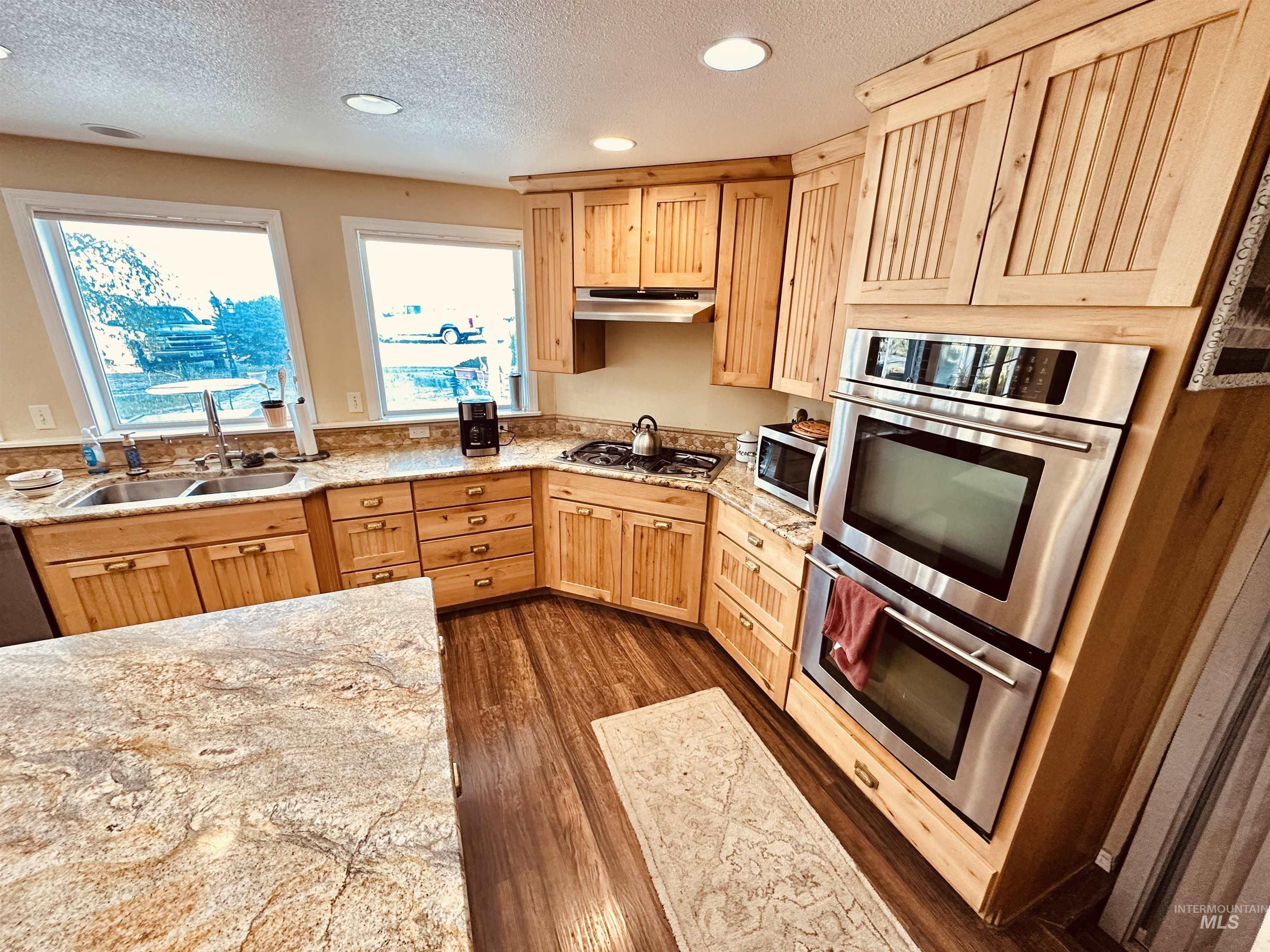 1049 Grand Avenue Nyssa, OR 97913 - Photo 8 of 50 Kitchen featuring wood-finish cabinetry, stone countertops, stainless steel appliances, and wood-finish flooring