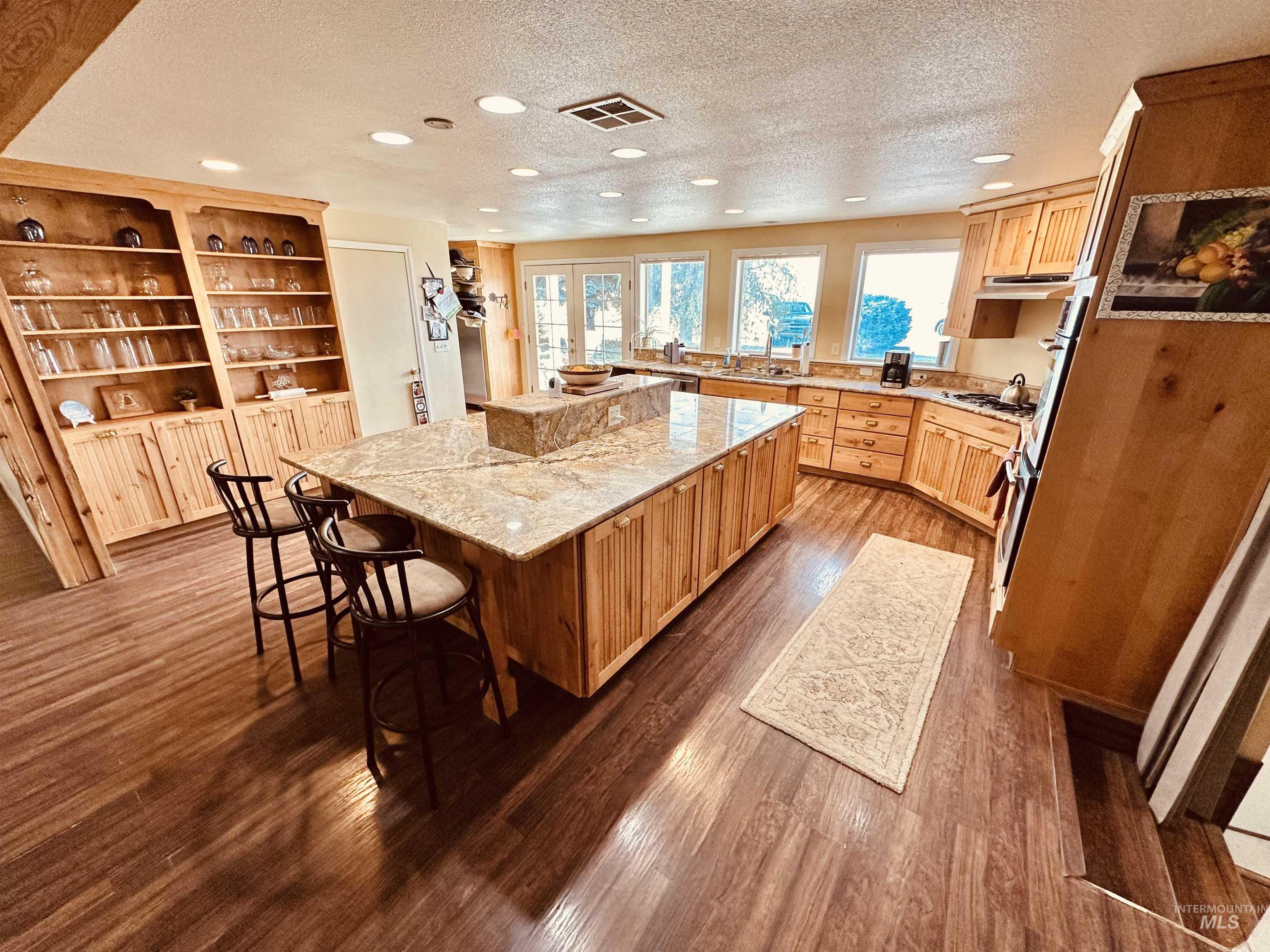 1049 Grand Avenue Nyssa, OR 97913 - Photo 10 of 50 Expansive kitchen featuring a large central island with a stone countertop, abundant wood cabinetry, wood-finish flooring, recessed lighting, and multiple windows