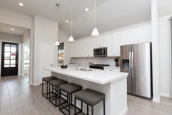a kitchen with a refrigerator a stove a sink and chairs