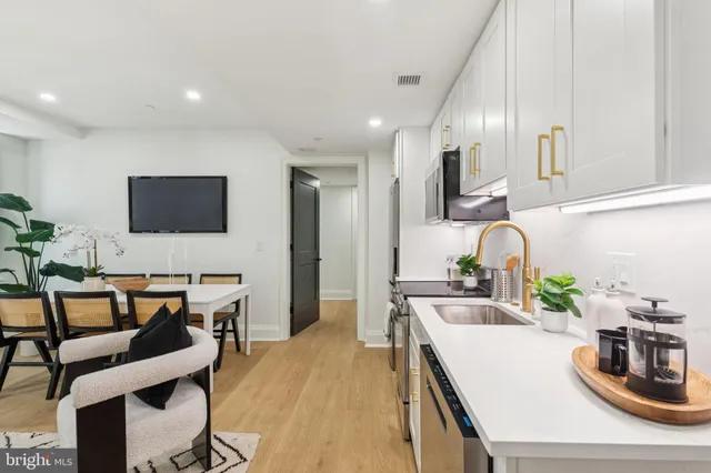 a kitchen with stainless steel appliances kitchen island granite countertop a sink and a stove top oven with wooden floor