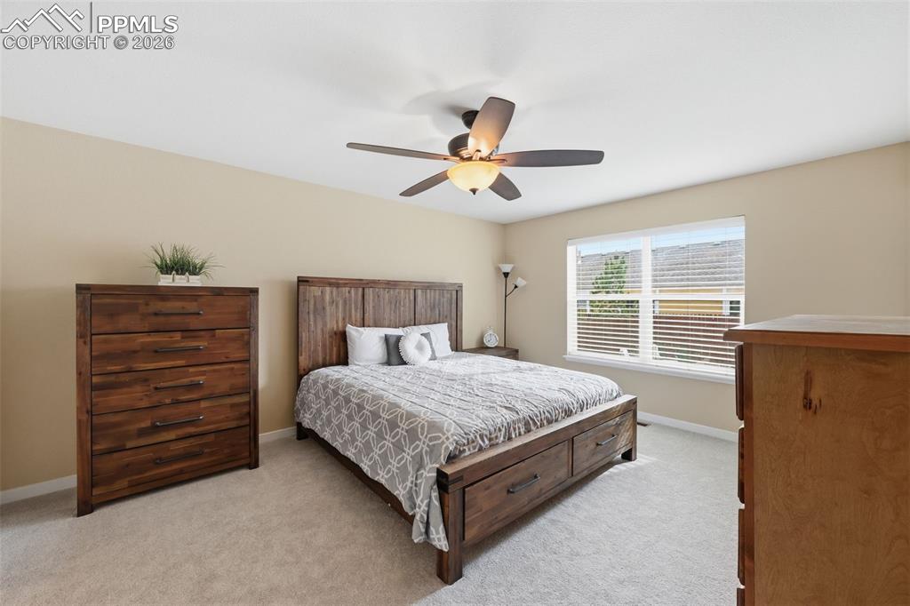 6565 Watusi Road Peyton, CO 80831 - Photo 19 of 36 a bedroom with a bed and a ceiling fan with a dresser