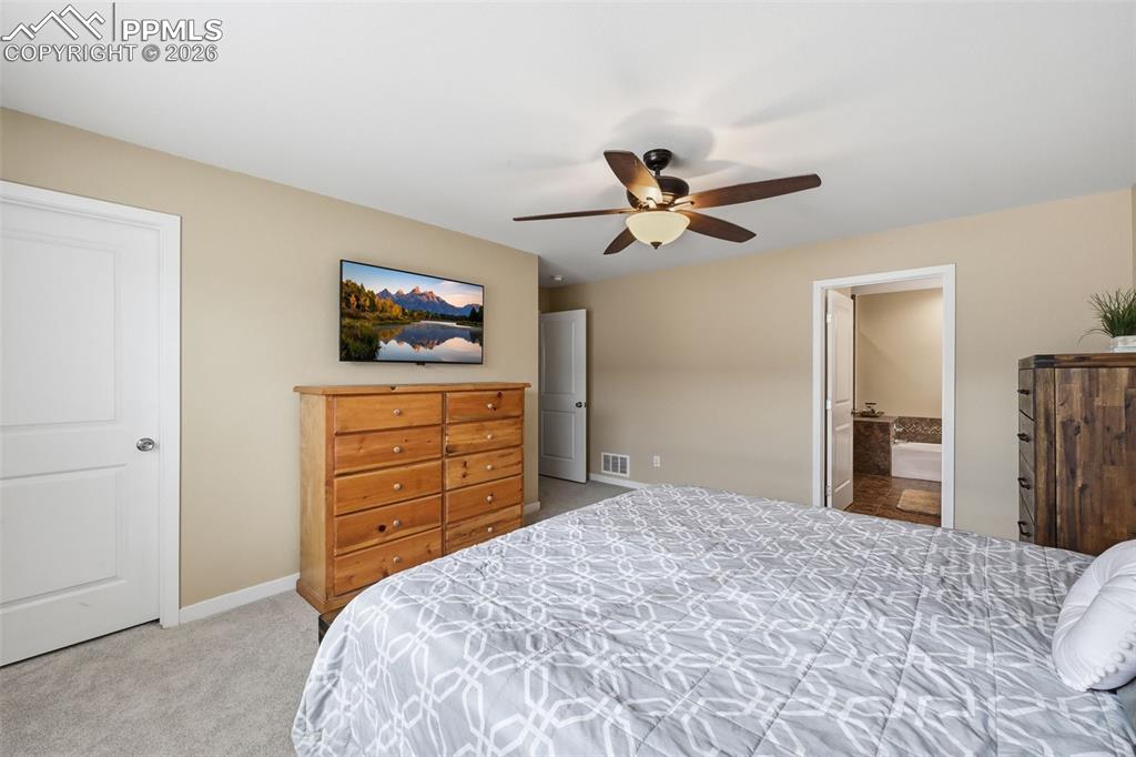 6565 Watusi Road Peyton, CO 80831 - Photo 21 of 36 a bedroom with a bed and a chandelier