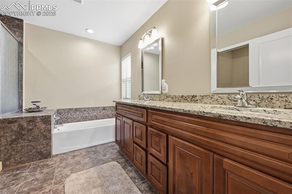6565 Watusi Road Peyton, CO 80831 - Photo 22 of 36 a bathroom with a granite countertop sink and a bathtub