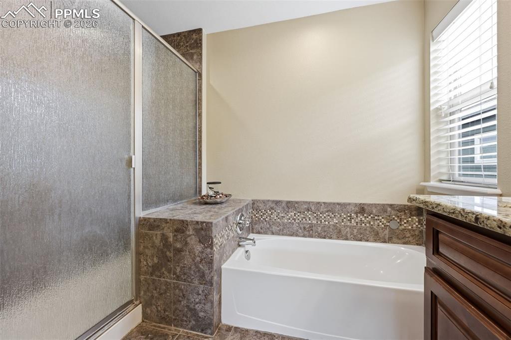6565 Watusi Road Peyton, CO 80831 - Photo 23 of 36 a bathroom with a granite countertop sink and a bathtub
