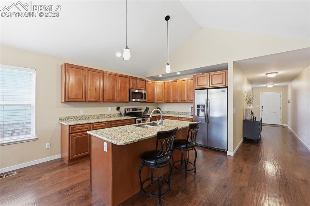 6565 Watusi Road Peyton, CO 80831 - Photo 10 of 36 a kitchen with stainless steel appliances granite countertop wooden floors stove refrigerator and cabinets