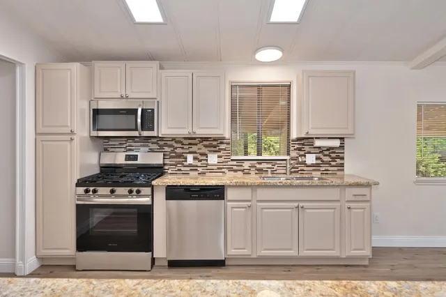 a kitchen with granite countertop a stove a sink and a microwave