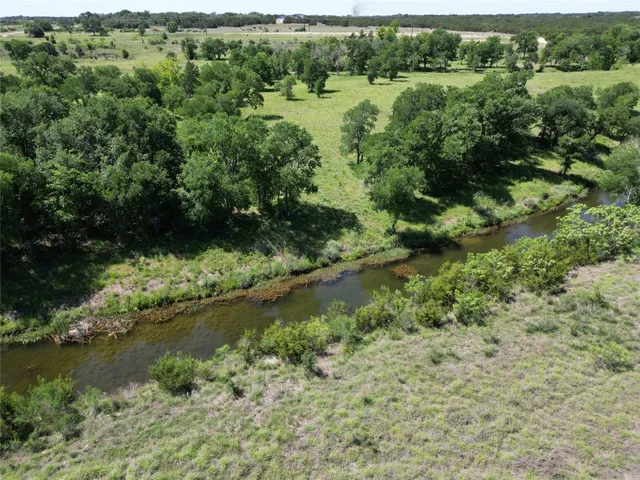 an aerial view of residential houses with outdoor space and trees