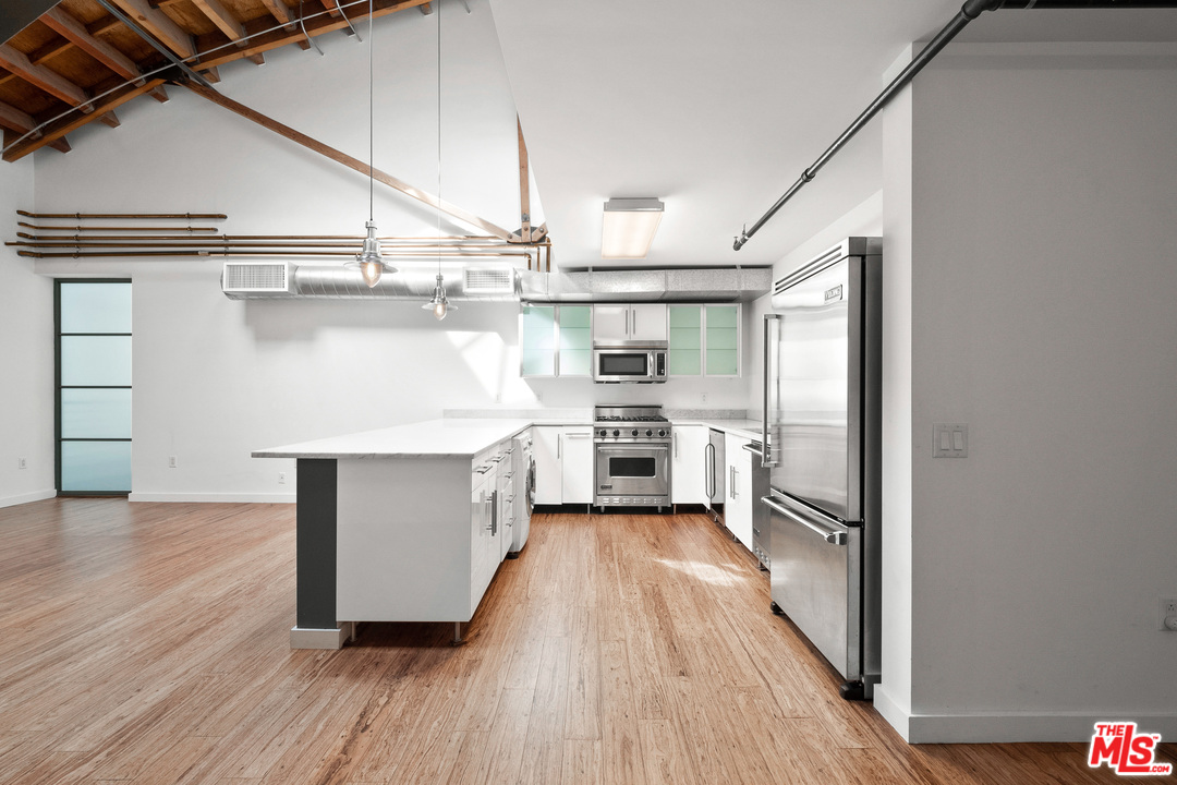 1046 Princeton Drive, Unit 210 Venice, CA 90292 - Photo 9 of 37 a kitchen with kitchen island a counter top space wooden floor stainless steel appliances and cabinets
