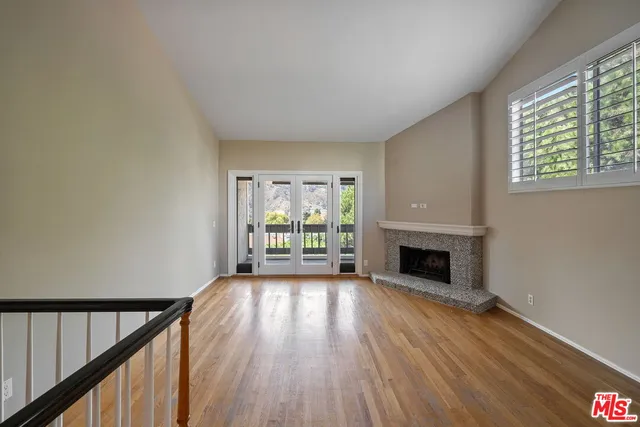 an empty room with wooden floor fireplace and windows
