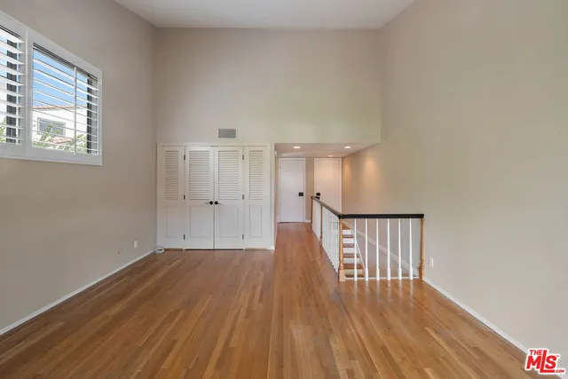 a view of an empty room with wooden floor and a fireplace