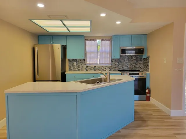 a kitchen with stainless steel appliances granite countertop a refrigerator a sink and a stove