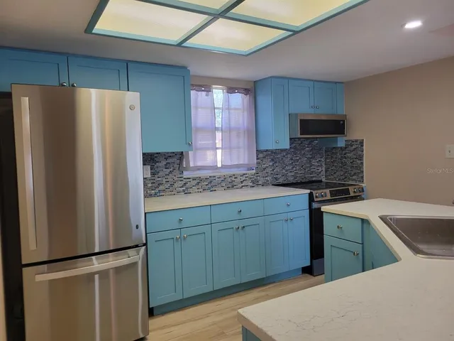 a kitchen with stainless steel appliances granite countertop a refrigerator and a sink