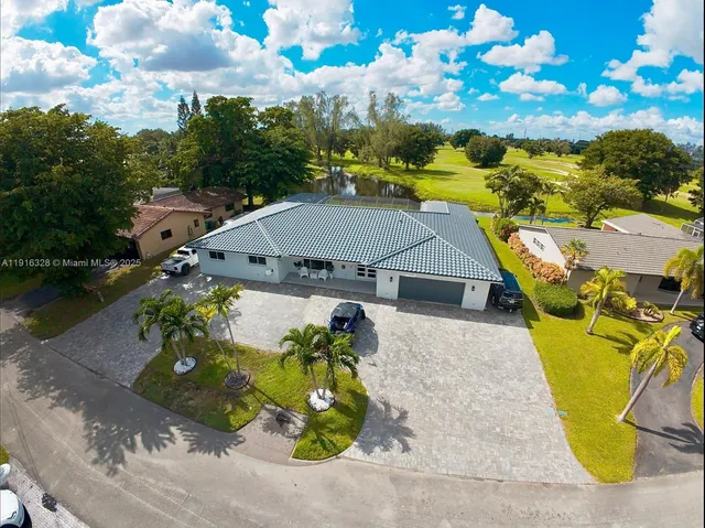 an aerial view of a house with swimming pool and large trees