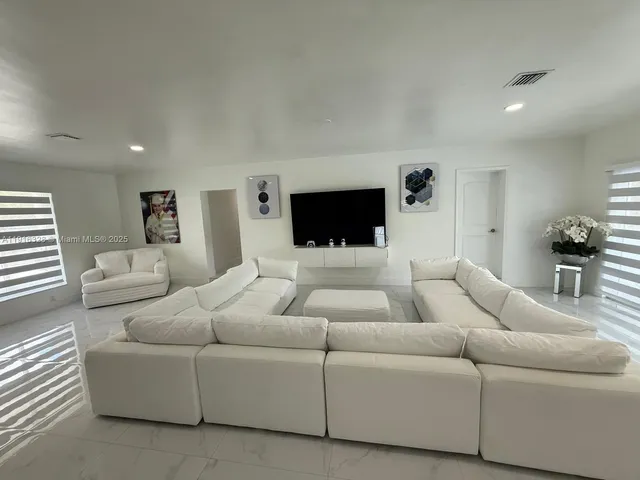 a large white kitchen with a sink and dishwasher a stove top oven with wooden floor