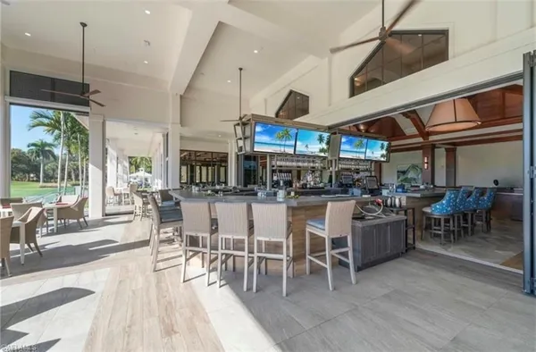 a room with lots of white furniture a large window and stainless steel appliances