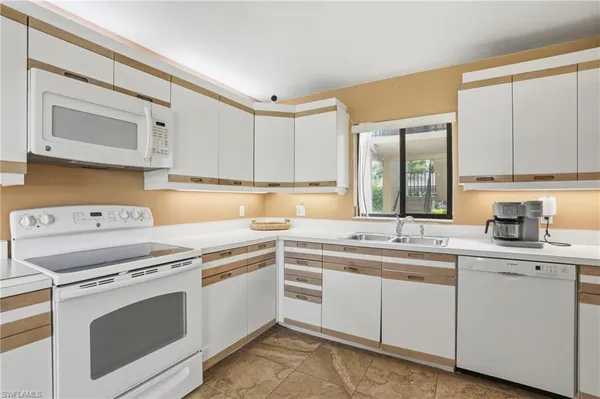 a kitchen with cabinets appliances a sink and a window