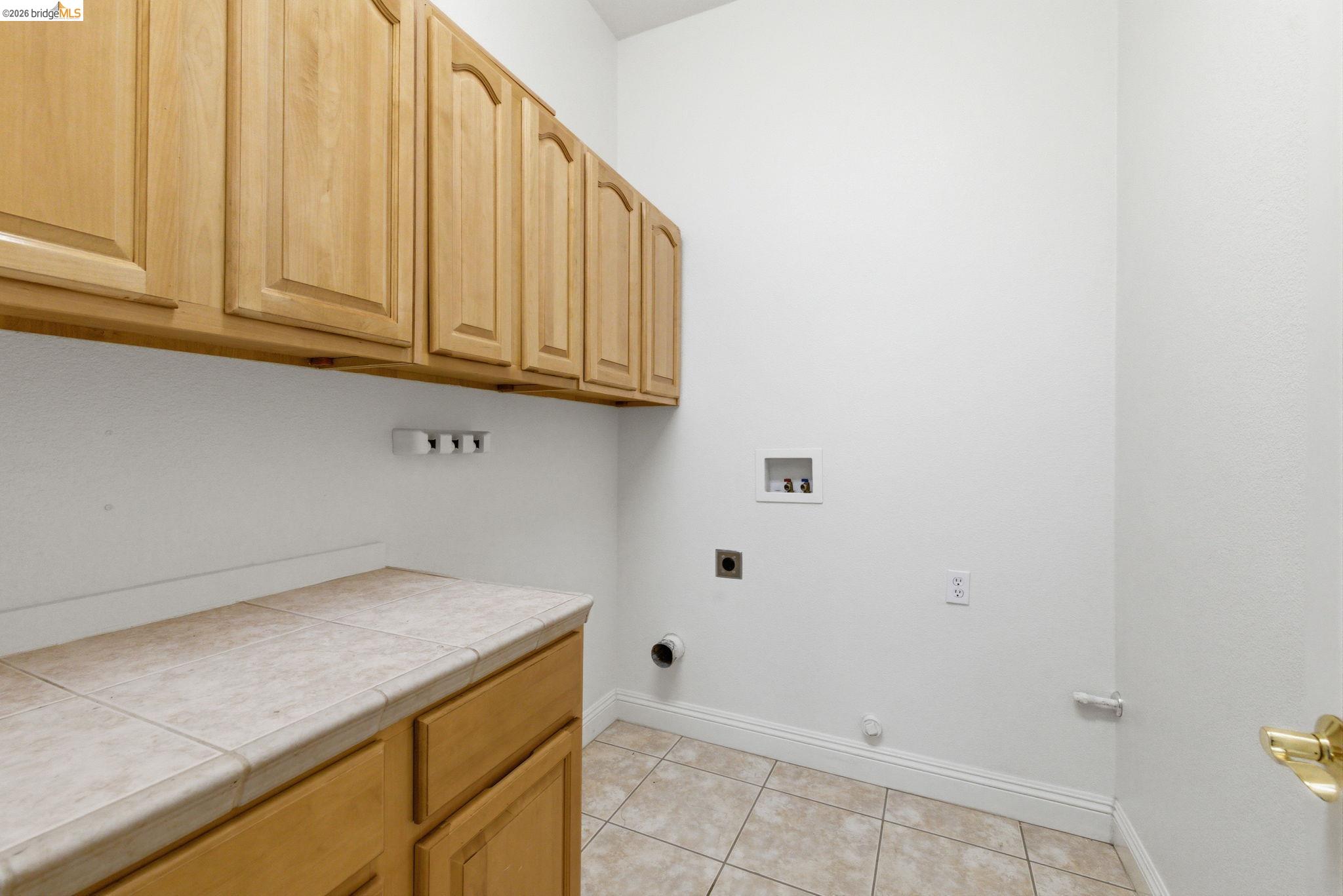 32 Apollo Lane Copperopolis, CA 95228 - Photo 24 of 58 Laundry room with cabinet space, washer hookup, light tile patterned flooring, hookup for a gas dryer, and electric dryer hookup